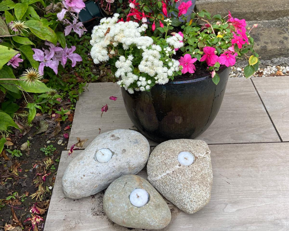 Three decorative candle stones with tea lights inside, resting on wooden planks.