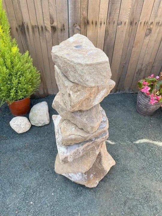 Medium golden granite water feature, 800mm, stacked with a hole on top, in a backyard setting.