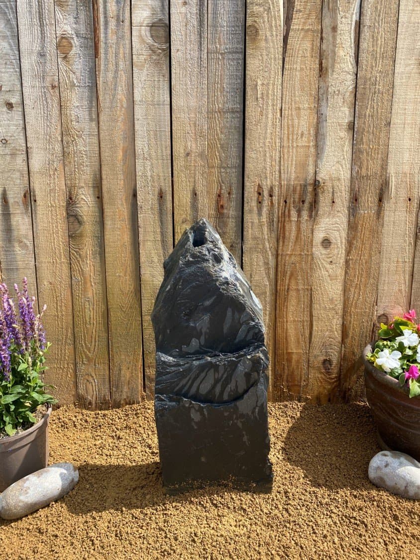 Slate monolith water feature by Water Feature C07, with natural stone texture, placed outdoors.
