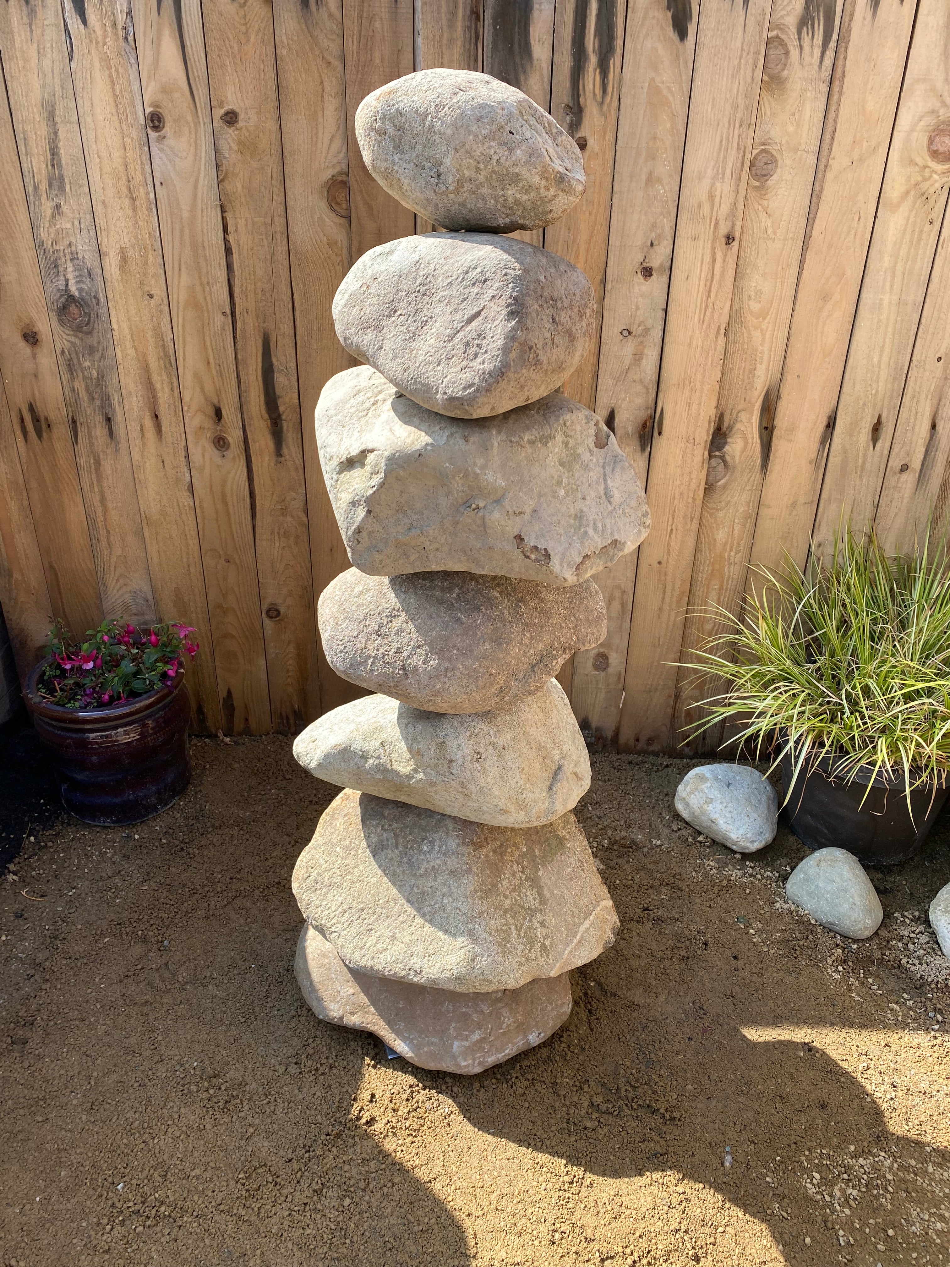 Natural pebble water feature in stacked stone construction, sitting on pea gravel.