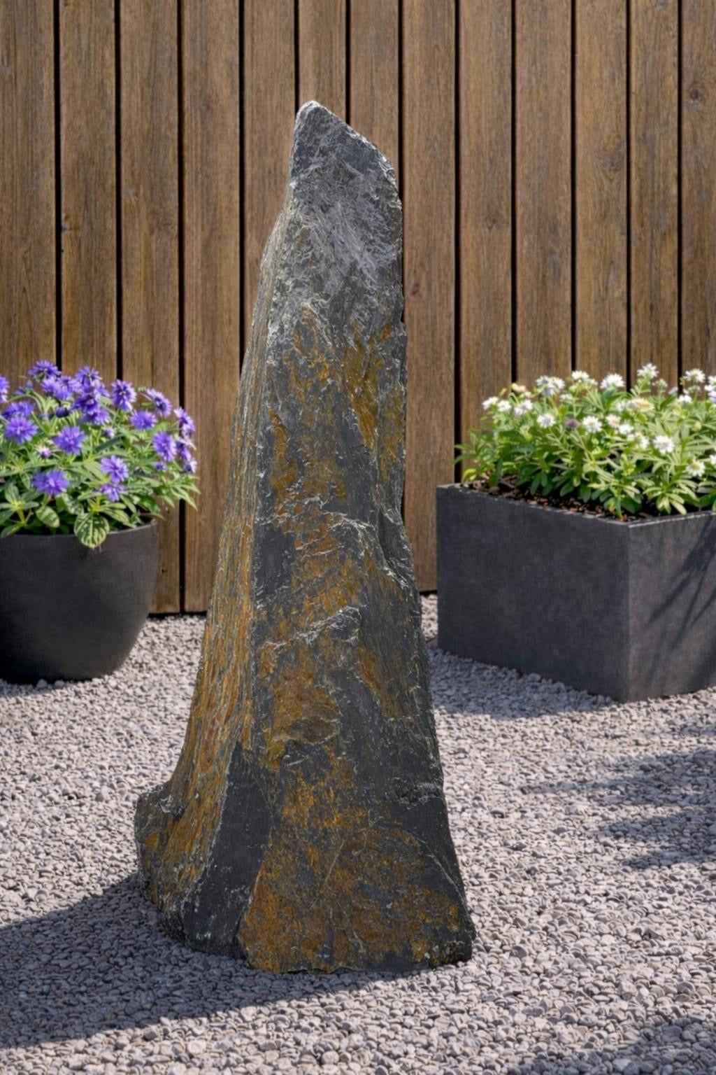 Slate monolith water feature by Water Feature with a natural stone texture, standing in a gravel garden.
