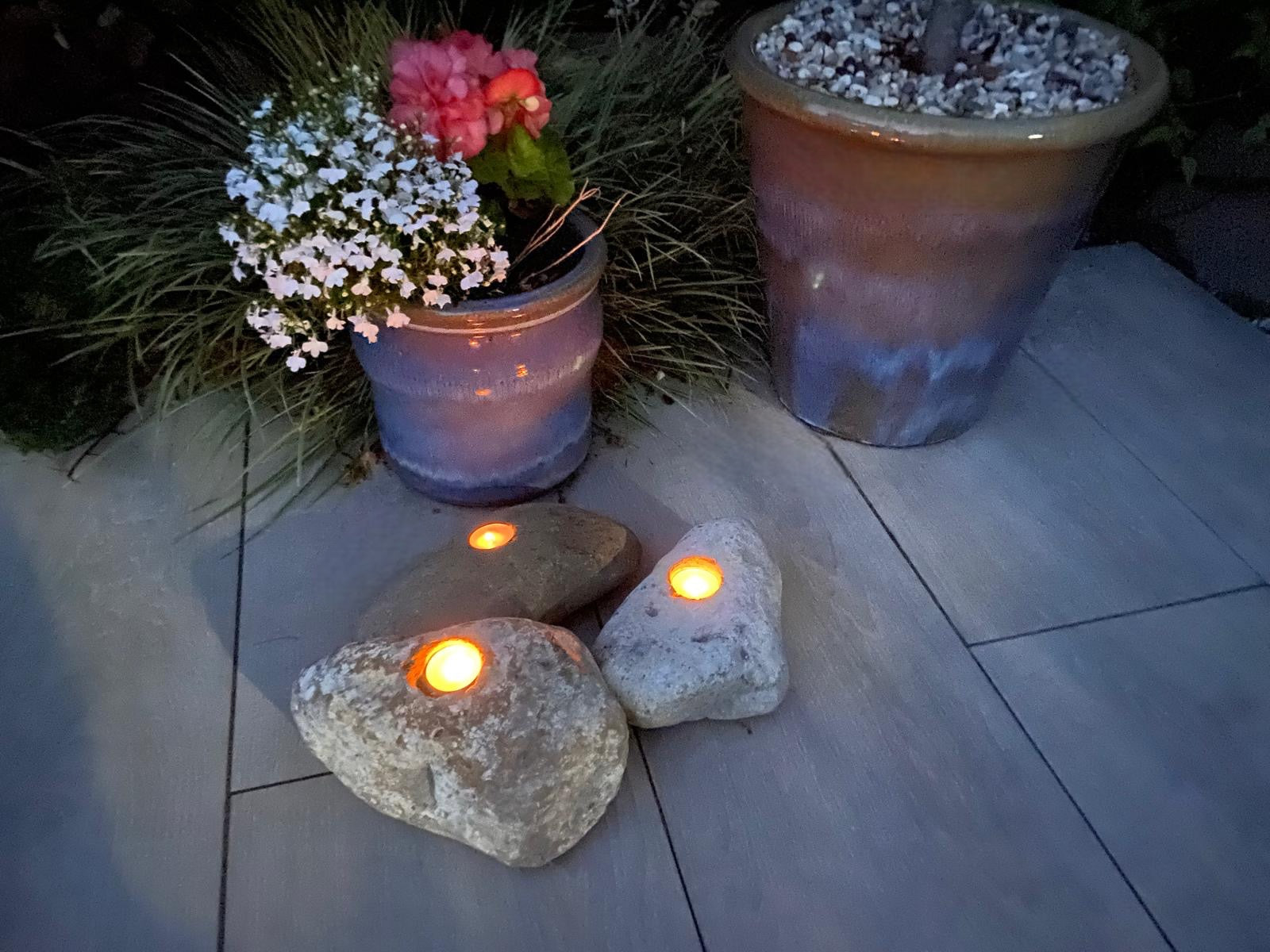 Decorative candle stones with single hole, surrounded by potted plants.