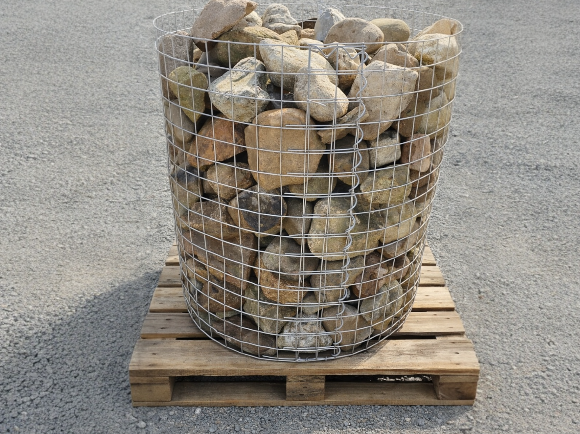Medium decorative garden boulders from 200-300mm, contained in a wire basket on a wooden pallet.