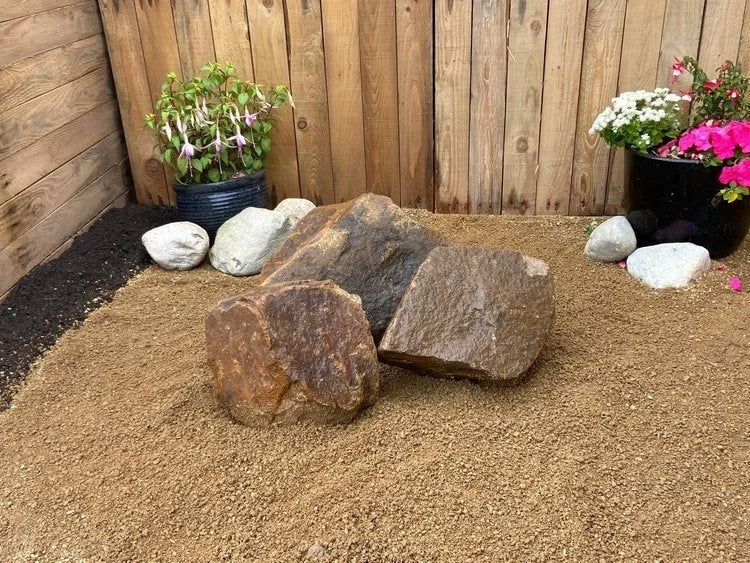 Golden granite rockery stones for gardens with rough texture in an outdoor setting.