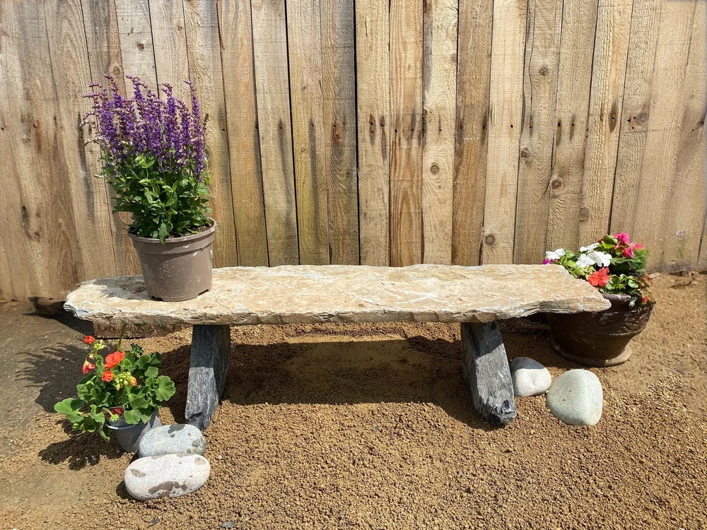 Large rustic slate pot stand with flowers and pebbles.