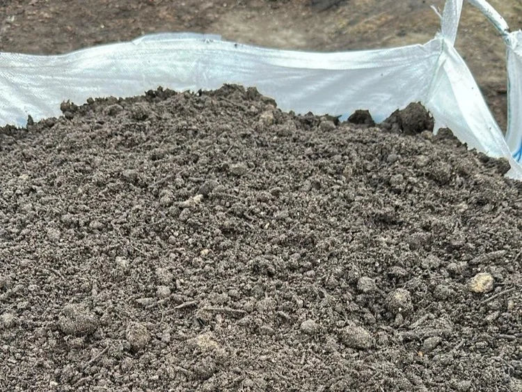 Pile of dark brown multi-purpose soil in a bulk bag, with an uneven texture.