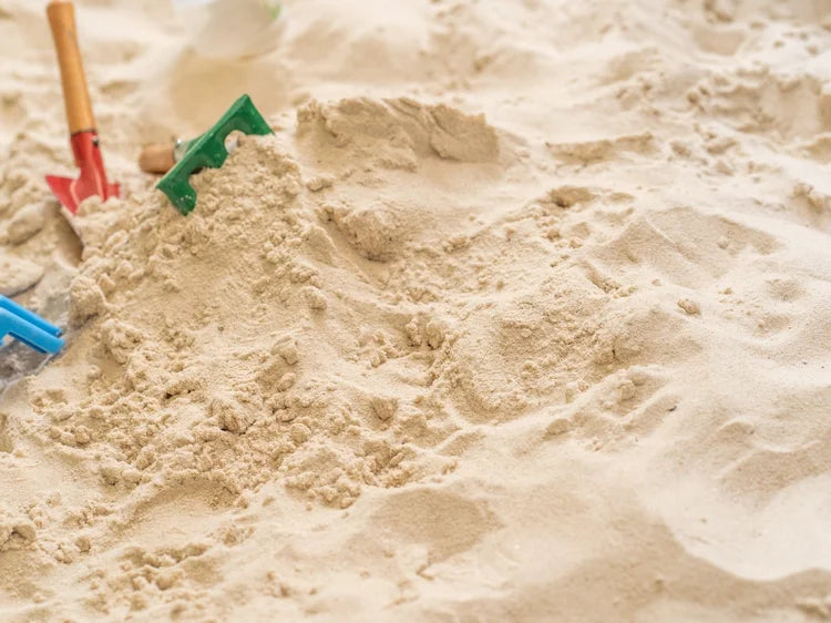 Beach play sand in bulk bag with various toys placed on the sand.