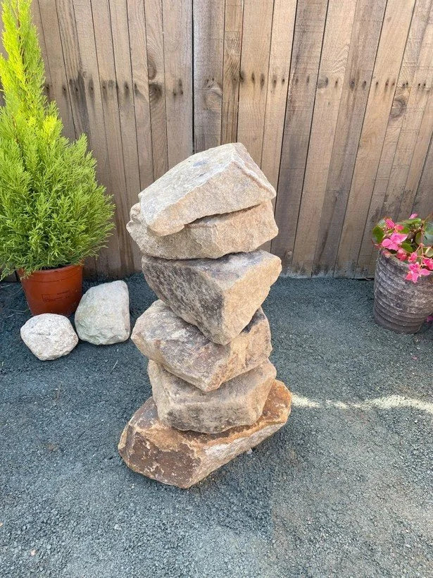 Small golden granite water feature by an unknown vendor, stacked with other stones in an outdoor setting.