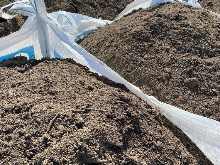 Bulk top soil by the bag, with dark brown earth and white synthetic straps.