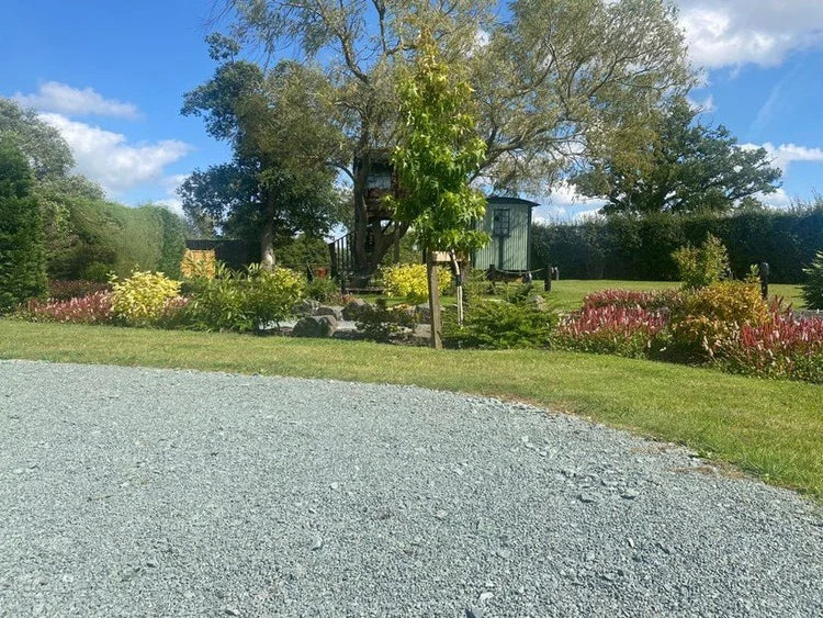 Green granite chippings for pond edging with 10mm size, over a gravel surface with the pond behind.