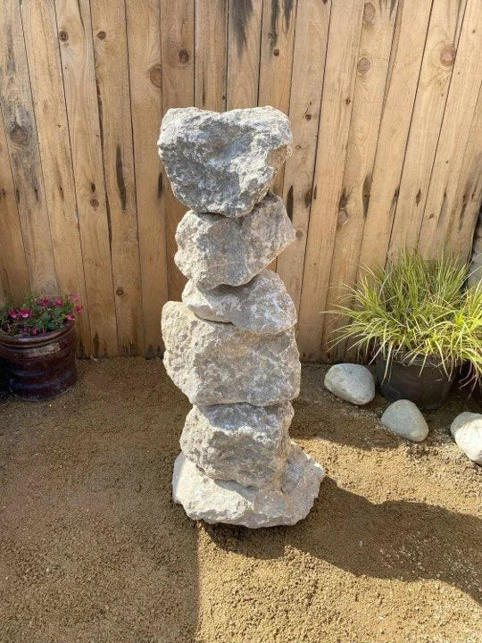 Medium grey limestone water feature by an unknown vendor, stacked in a column outdoors.
