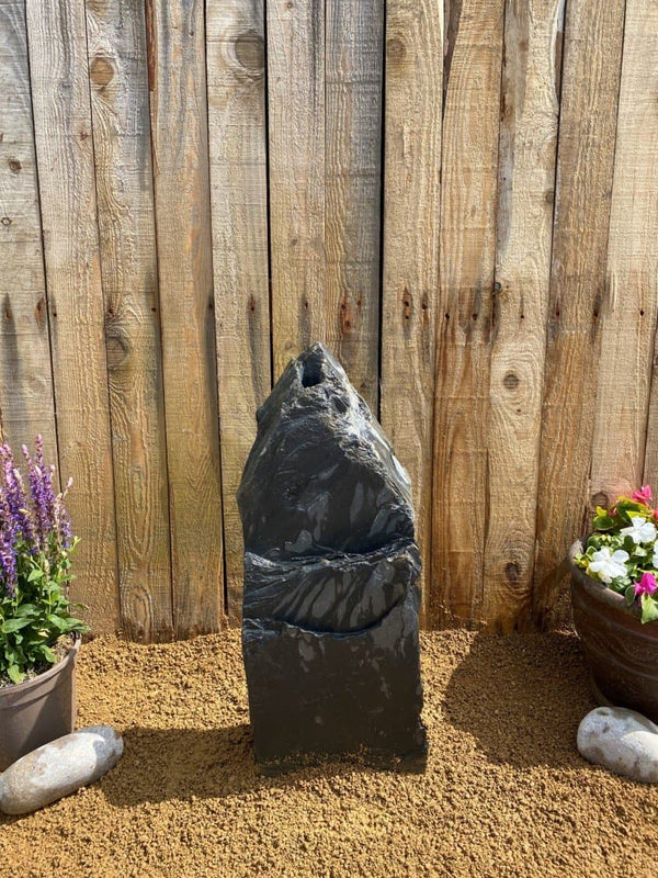 Slate monolith water feature by Water Feature C07, with natural stone texture, placed outdoors.
