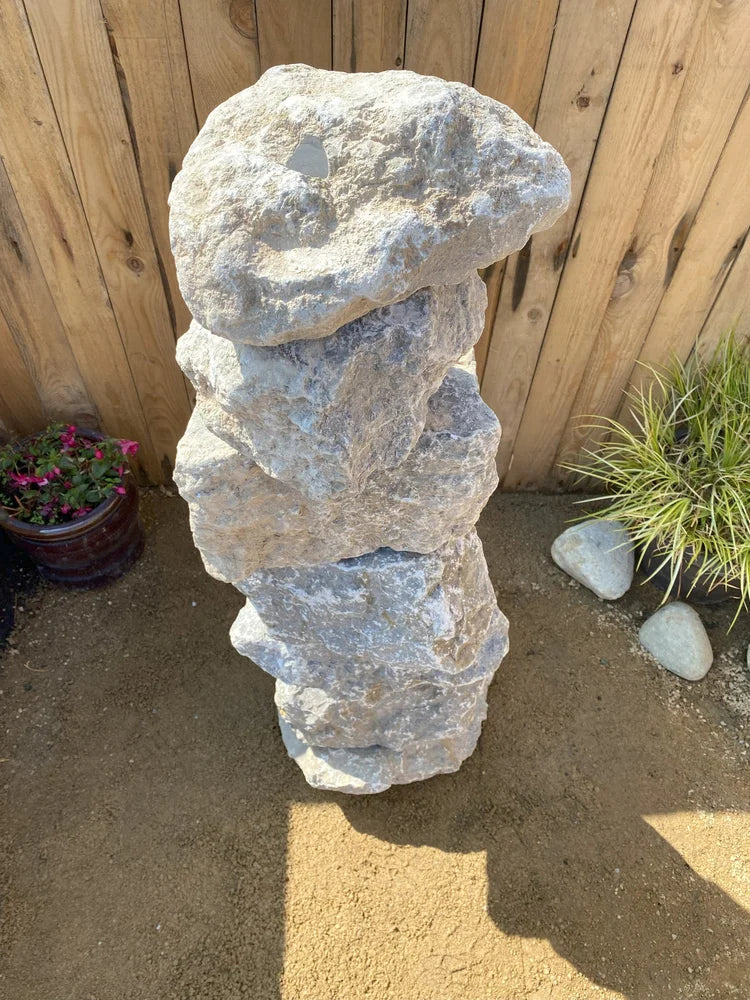 Large grey limestone water feature, one meter tall, with a weathered texture.