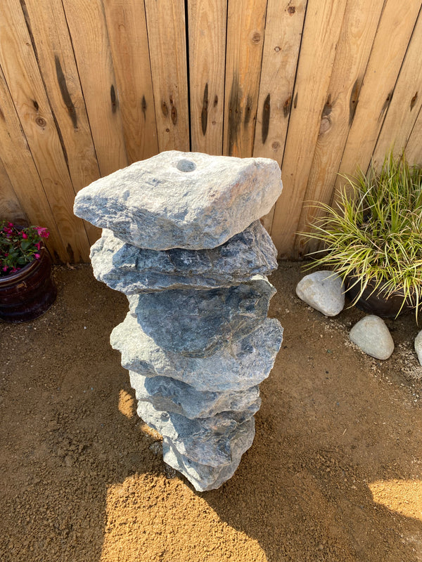 Green granite water feature, 800mm, with stacked rock design, adjacent to plants and mulch.