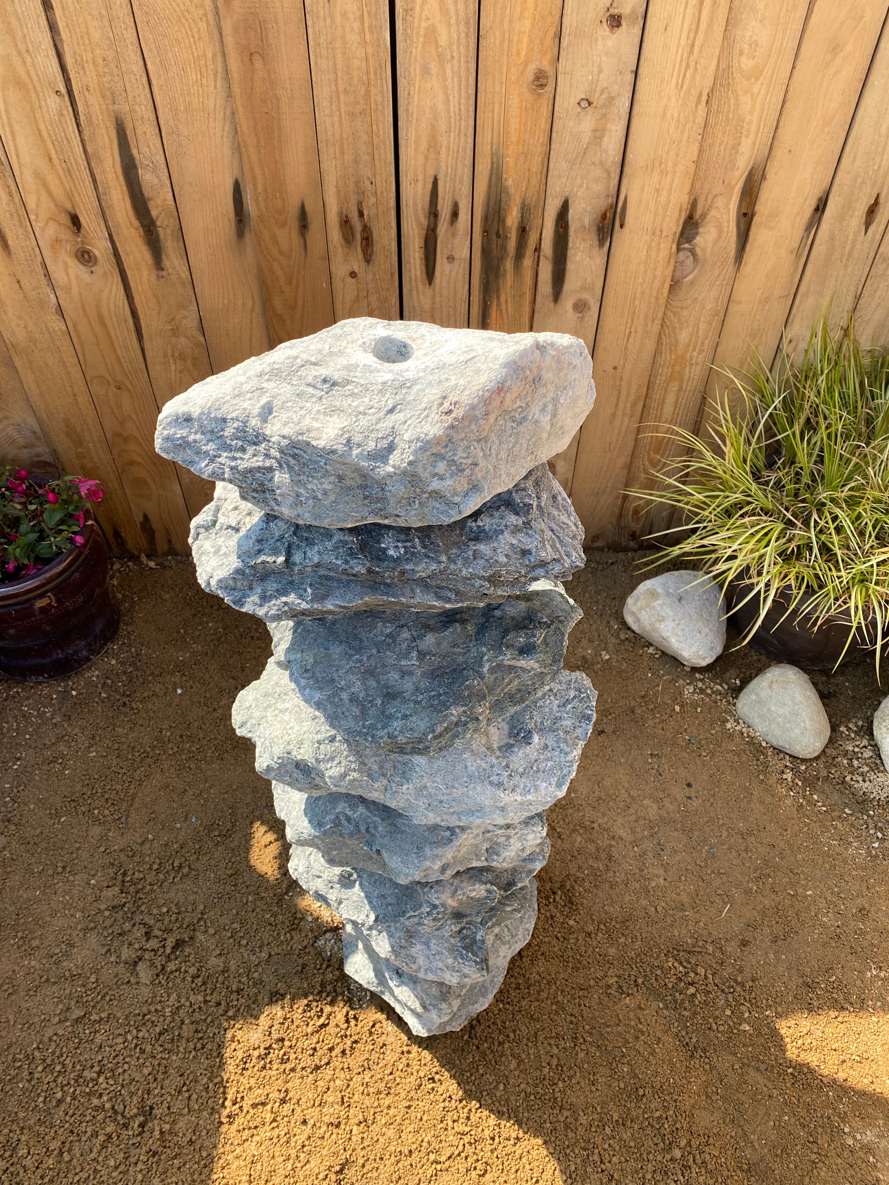 Green granite water feature, 800mm, with stacked rock design, adjacent to plants and mulch.