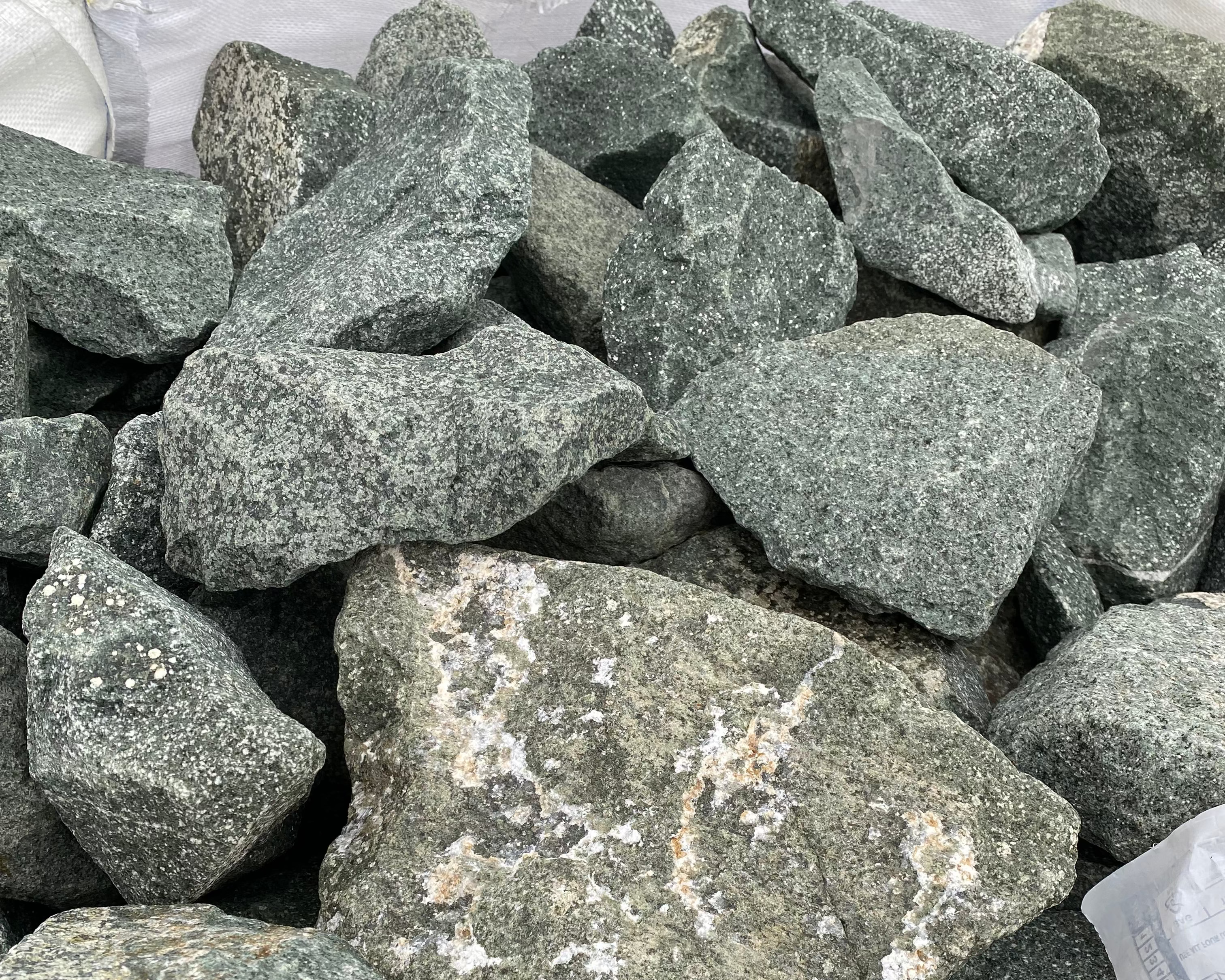 Green granite gabion stones for gabion baskets, with speckled texture.