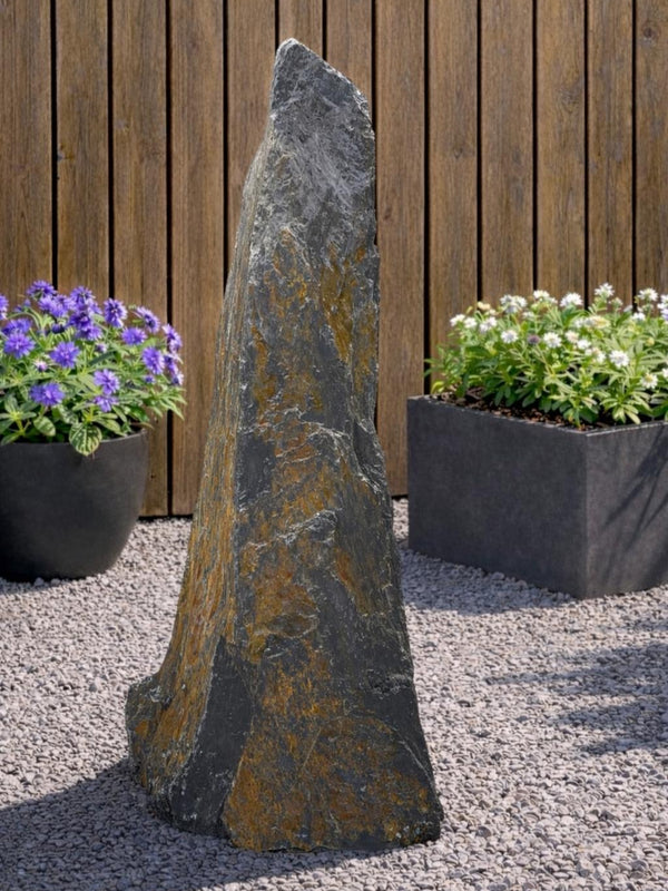Slate monolith water feature by Water Feature with a natural stone texture, standing in a gravel garden.