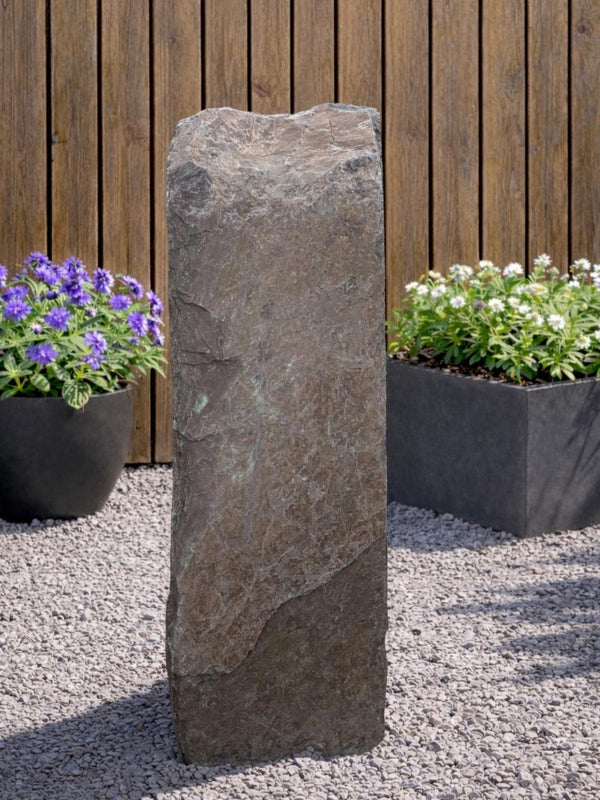 Slate monolith water feature by Water Feature 112 standing outdoors on gravel.