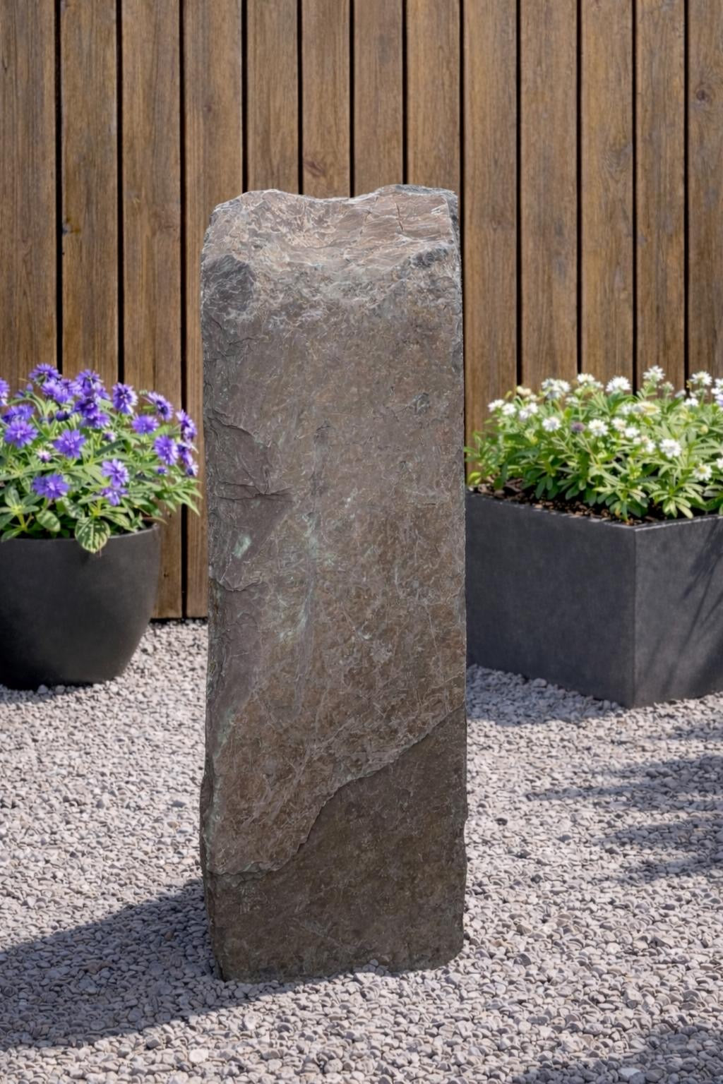 Slate monolith water feature by Water Feature 112 standing outdoors on gravel.