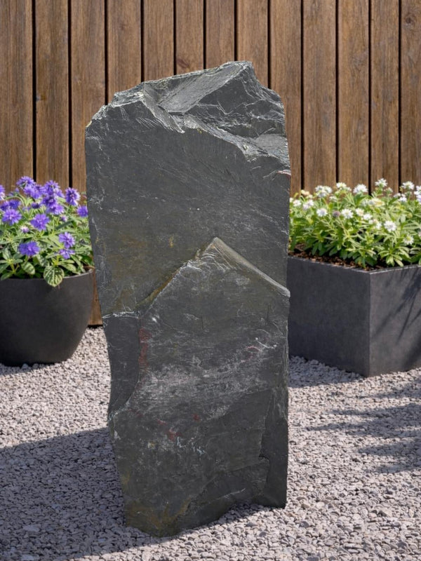 Grey slate monolith standing stone by 133 with rugged, uneven texture and natural looking rock formation.