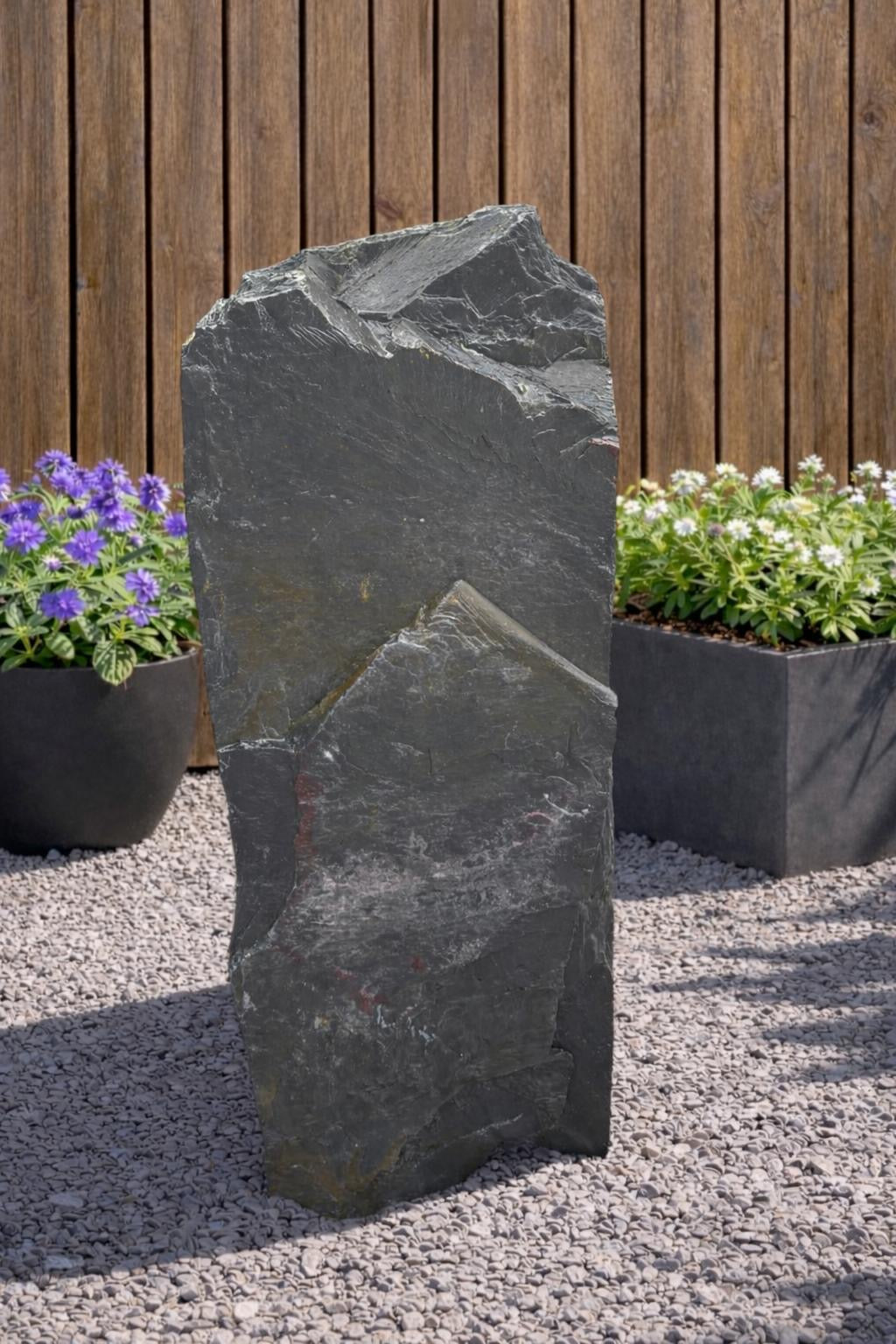 Grey slate monolith standing stone by 133 with rugged, uneven texture and natural looking rock formation.