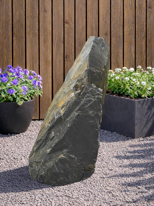 Grey slate monolith feature stone by Decorative Aggregates with natural stone texture, standing outdoors between plants.