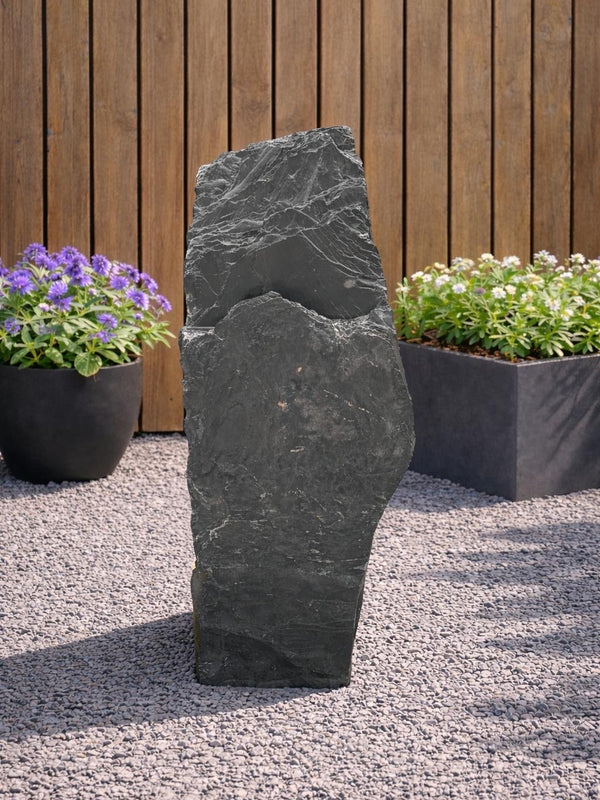 Grey slate monolith feature stone by Unbranded, standing upright on a gravel bed in a garden setting.