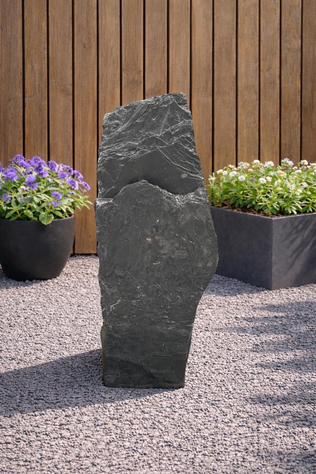 Grey slate monolith feature stone by Unbranded, standing upright on a gravel bed in a garden setting.