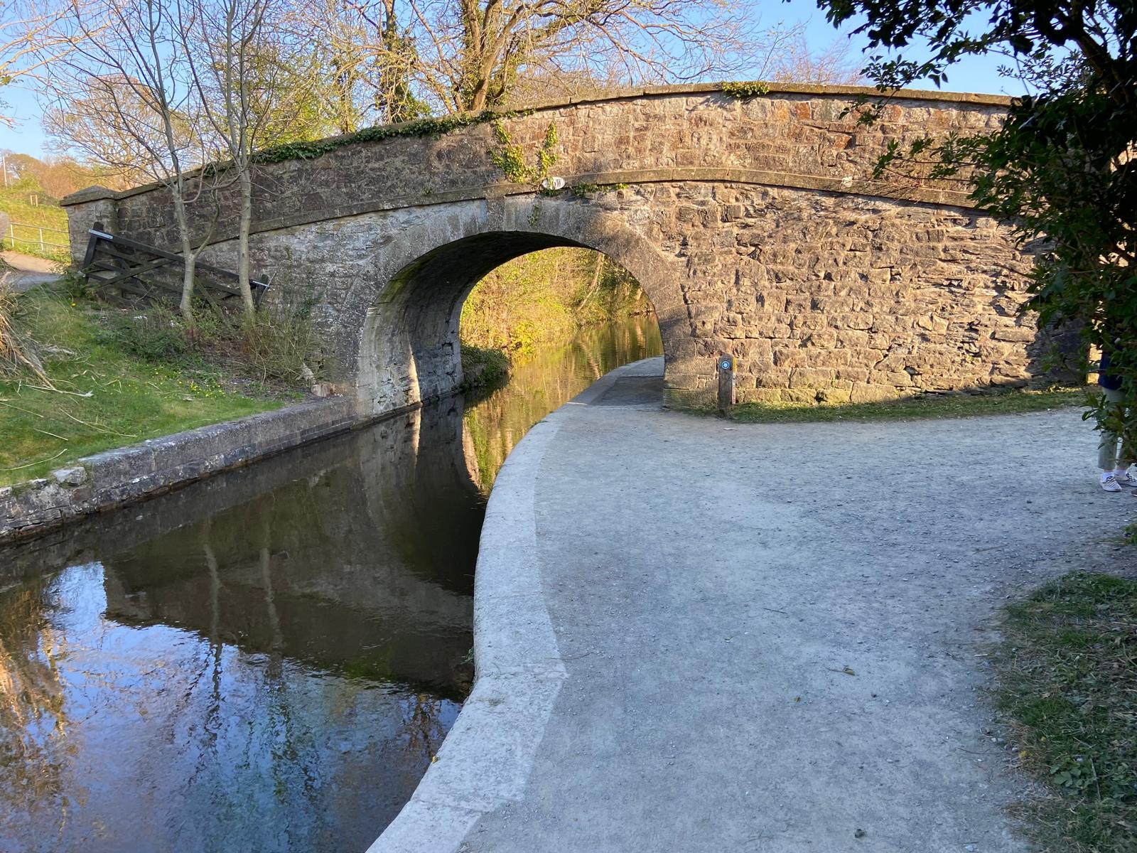 Green granite self binding gravel for driveways, textured, next to a canal and stone bridge.
