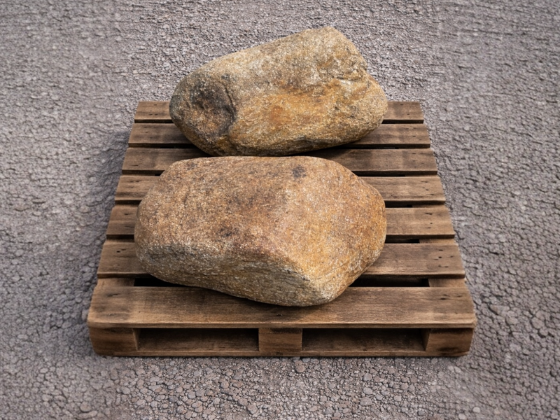 Two tan decorative garden boulders, on a wooden pallet.

