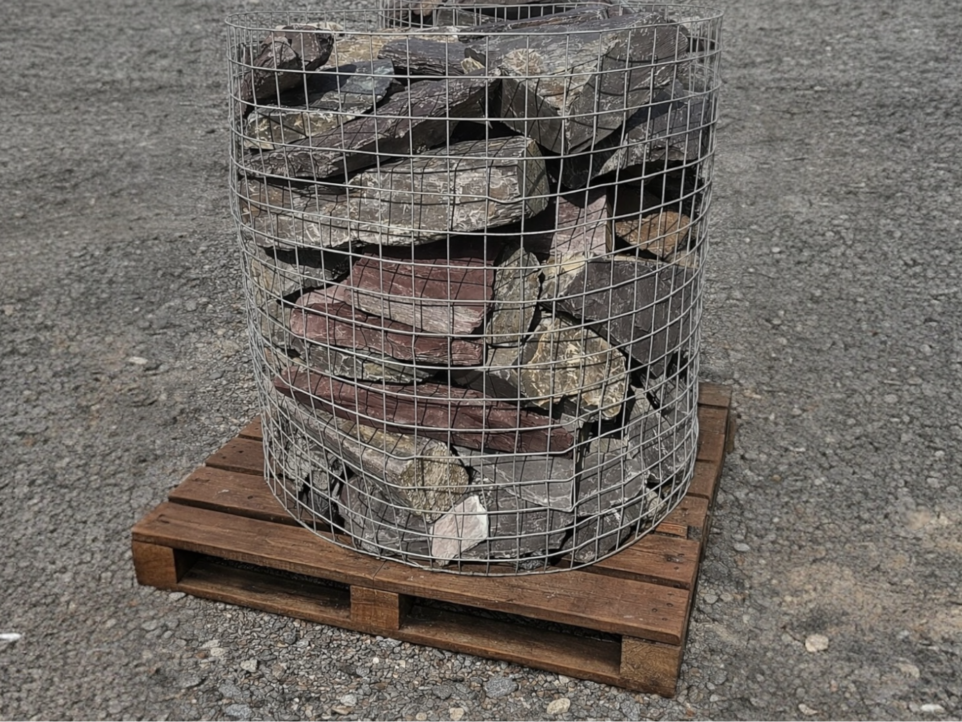 Plum slate walling stone for landscapes with a wire cage, on a wood pallet.
