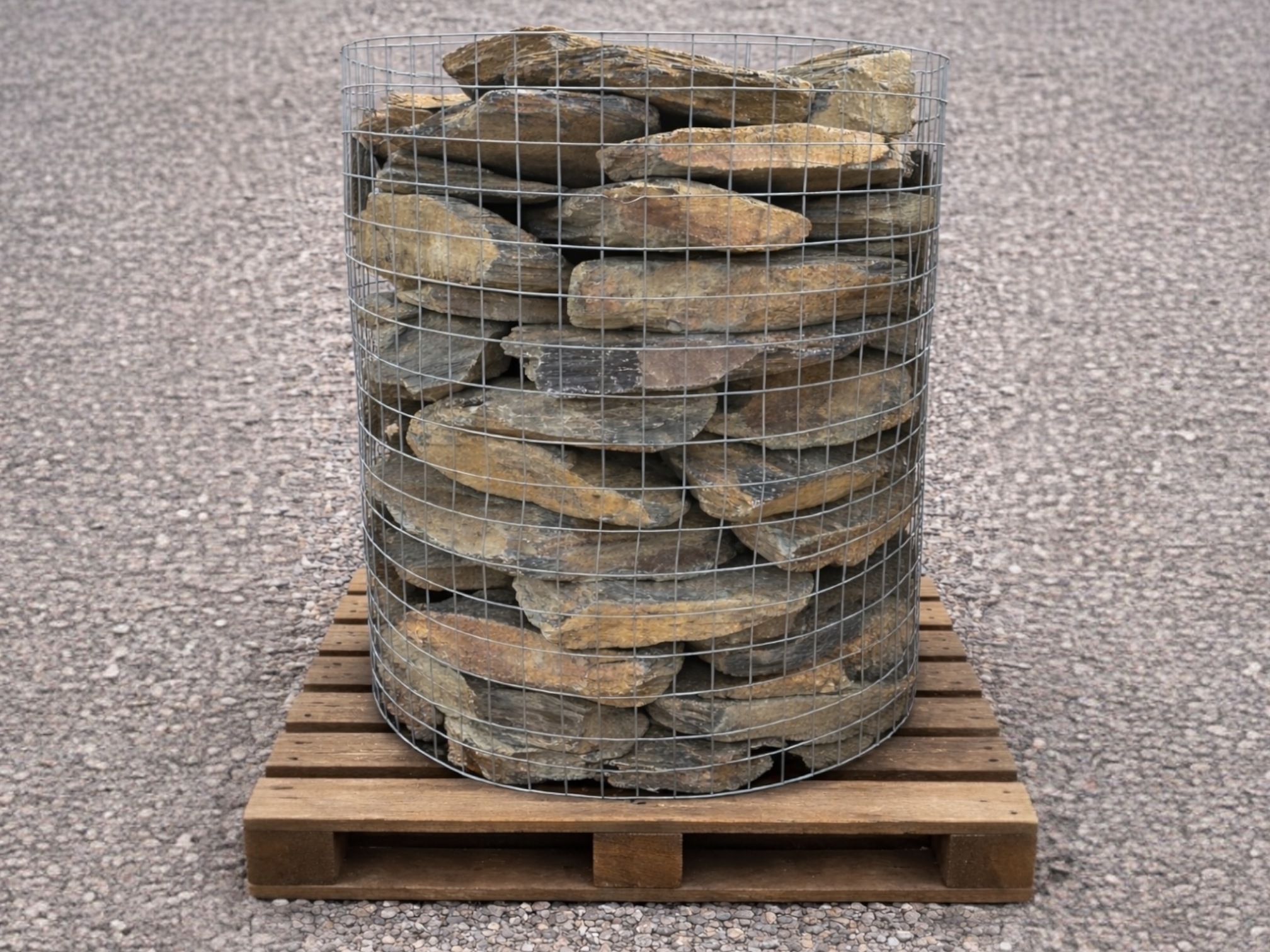 Rustic grey slate stone walling for landscapes filled in a wire cage on a wooden pallet.