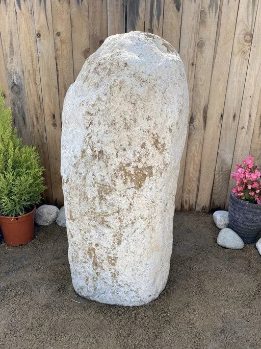 Boulder monolith standing stone by G02 with a rough, weathered texture, positioned against a wooden fence.