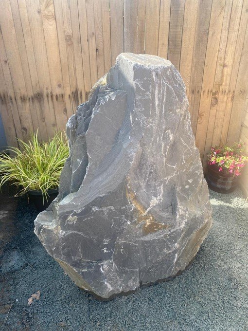 Grey slate monolith standing stone, about 990mm tall, with natural, rugged texture near a wooden fence.