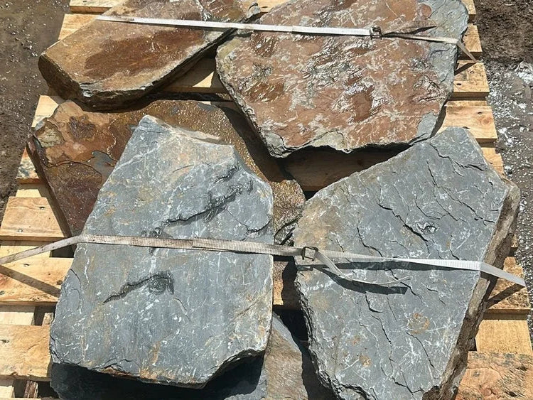 Natural slate stepping stones for gardens with grey and brown color variations, resting on a wooden pallet.