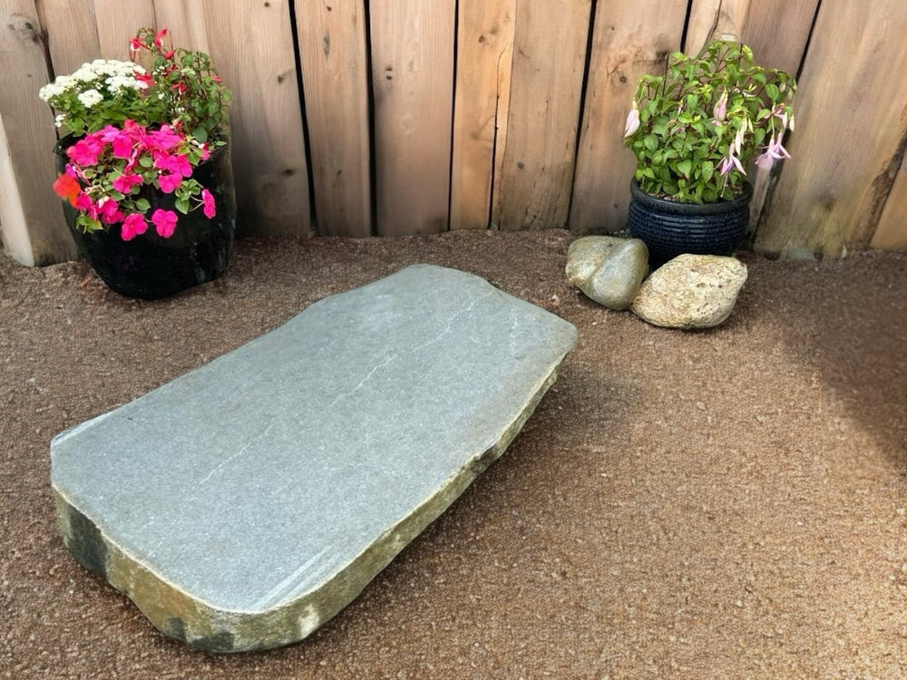 Large sawn boulder stepping stone for ponds with a flat gray surface and rounded sides.
