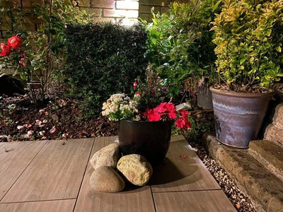 Natural glacial pond cobbles, 100-200mm, in varying light neutral tones, positioned on wooden pavers in an outdoor garden setting.
